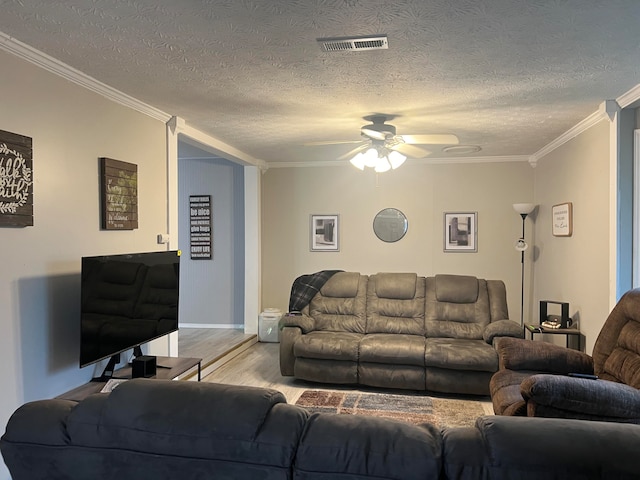 living room with crown molding, ceiling fan, light hardwood / wood-style floors, and a textured ceiling