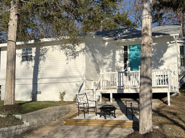 rear view of property featuring an outdoor fire pit and a wooden deck