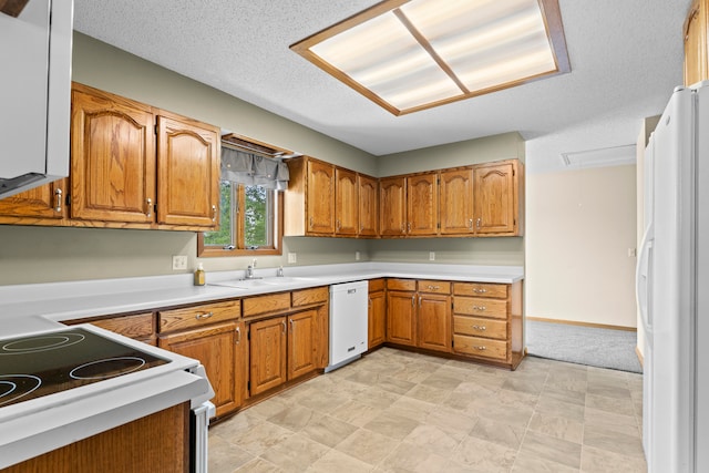 kitchen with sink, white appliances, and a textured ceiling