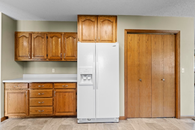 kitchen featuring white refrigerator with ice dispenser and a textured ceiling