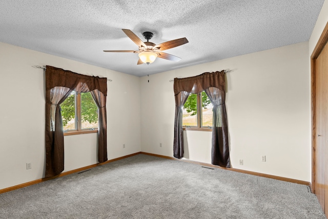 spare room with a textured ceiling, carpet floors, and ceiling fan