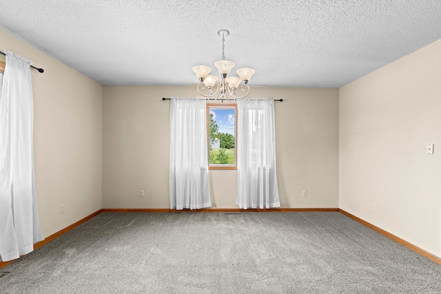 carpeted spare room featuring a chandelier and a textured ceiling