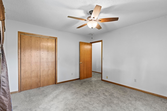 unfurnished bedroom featuring ceiling fan, light colored carpet, a textured ceiling, and a closet