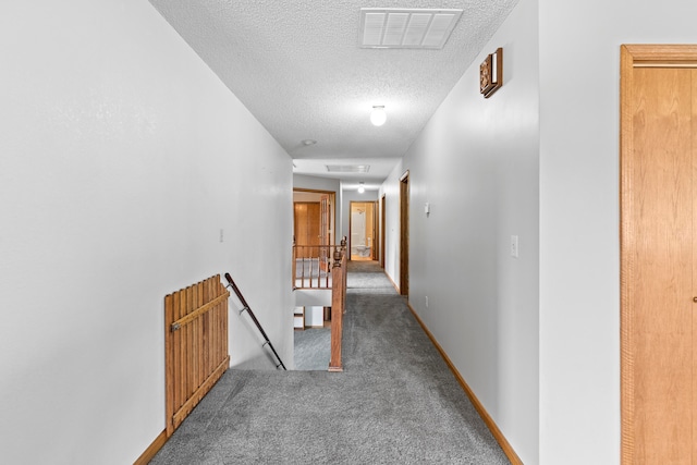 hall featuring carpet floors and a textured ceiling