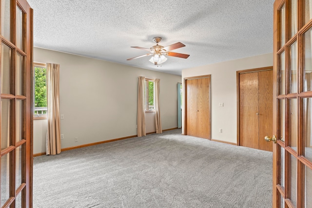 carpeted spare room with french doors, a textured ceiling, and ceiling fan