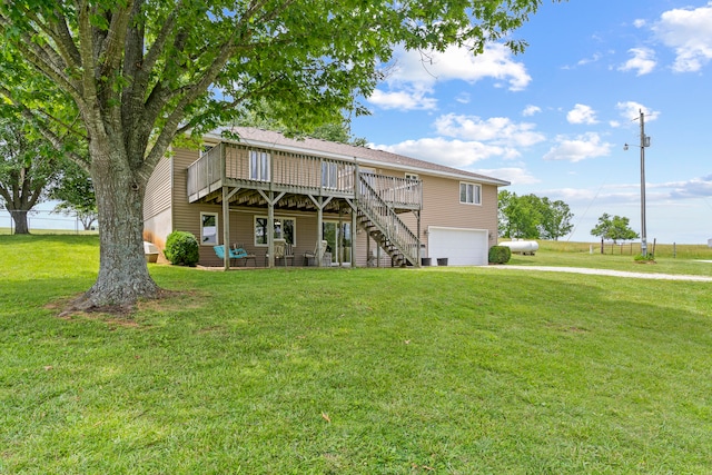 rear view of property with a lawn, a garage, and a wooden deck