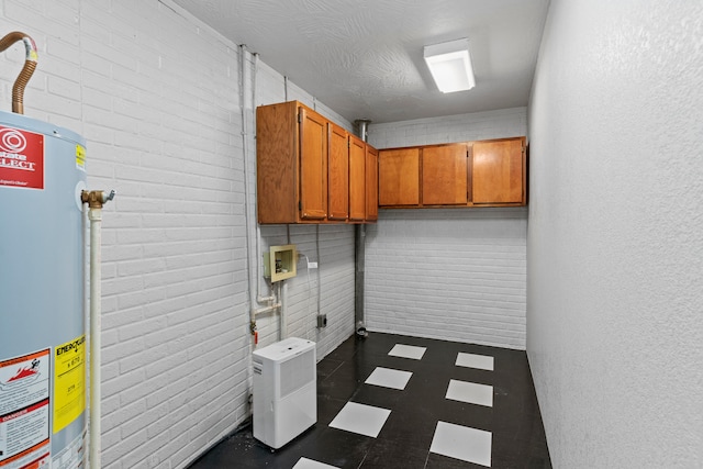 clothes washing area featuring cabinets, gas water heater, washer hookup, electric dryer hookup, and a textured ceiling