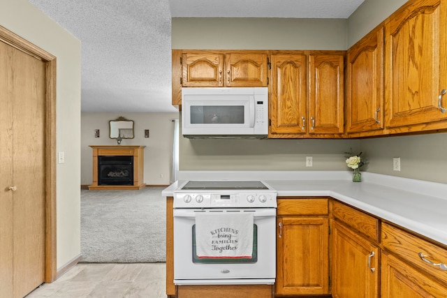 kitchen with light colored carpet, white appliances, and a textured ceiling