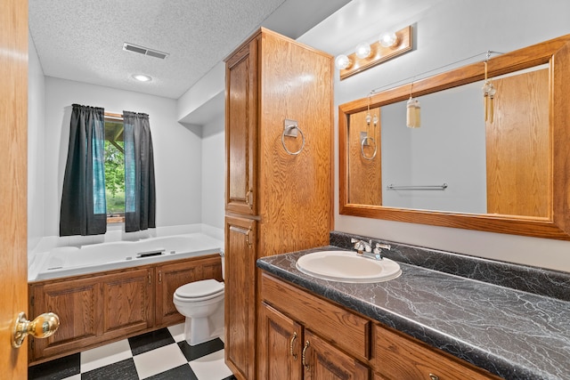 bathroom featuring vanity, a bath, a textured ceiling, and toilet