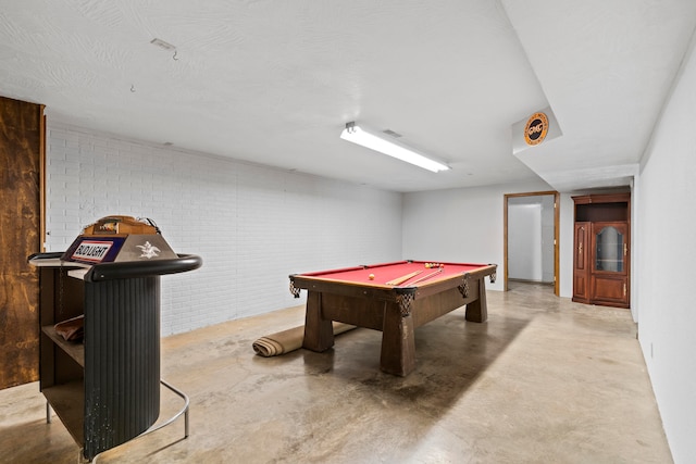 recreation room with concrete flooring, brick wall, and billiards