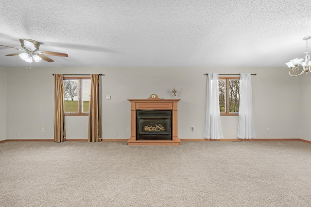 unfurnished living room featuring carpet flooring, a textured ceiling, ceiling fan with notable chandelier, and plenty of natural light