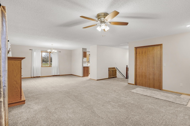 spare room with light carpet, a textured ceiling, and ceiling fan with notable chandelier