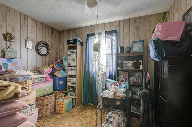 miscellaneous room featuring ceiling fan, wood walls, carpet floors, and a textured ceiling