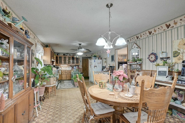 dining space with a textured ceiling and ceiling fan with notable chandelier