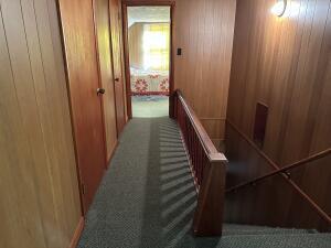312 E Maple St, West Plains, MO 65775 - hall with carpet floors, wood walls, and an upstairs landing