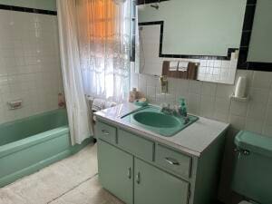 full bathroom featuring backsplash, toilet, shower / bath combo with shower curtain, vanity, and tile walls