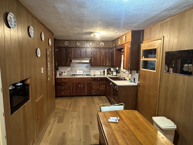 312 E Maple St, West Plains, MO 65775 - kitchen featuring light wood-style floors, under cabinet range hood, wood walls, light countertops, and black appliances