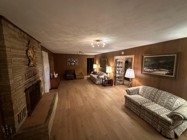 312 E Maple St, West Plains, MO 65775 - living area with light wood-type flooring, a fireplace, wood walls, and a textured ceiling