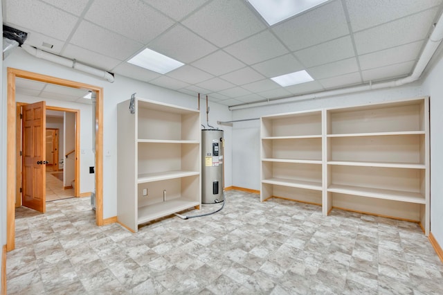 basement featuring a drop ceiling and water heater