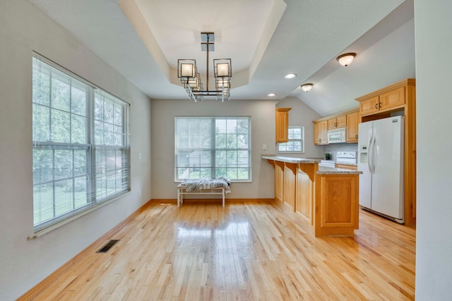 kitchen featuring white appliances, hanging light fixtures, light wood-type flooring, a kitchen bar, and kitchen peninsula