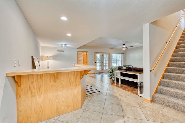 kitchen with ceiling fan, french doors, tile patterned flooring, kitchen peninsula, and a kitchen bar