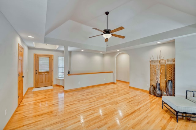 living room featuring light hardwood / wood-style floors, a raised ceiling, and ceiling fan