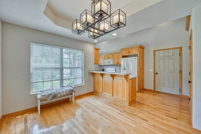 kitchen with kitchen peninsula, light wood-type flooring, white appliances, hanging light fixtures, and a breakfast bar area