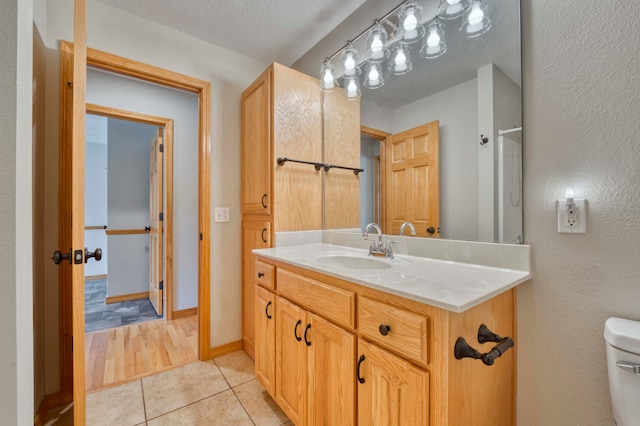 bathroom with tile patterned flooring, vanity, toilet, and a textured ceiling