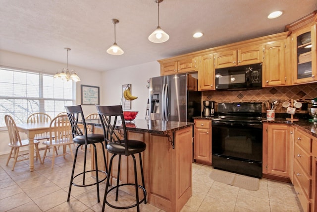 kitchen featuring a breakfast bar, black appliances, hanging light fixtures, a kitchen island, and backsplash