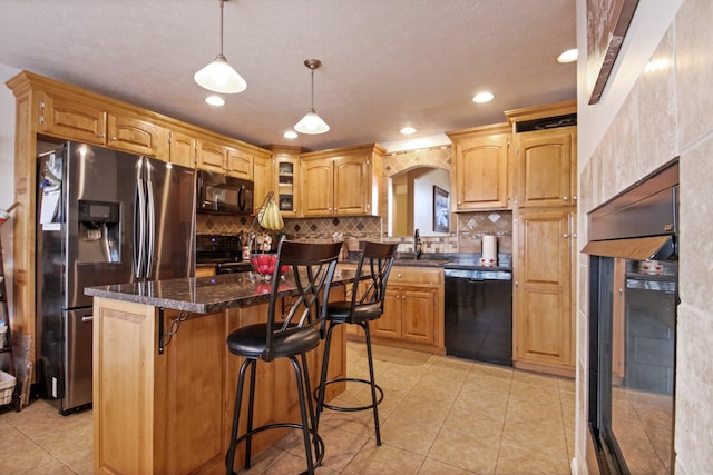 kitchen featuring sink, a breakfast bar, a center island, black appliances, and decorative backsplash