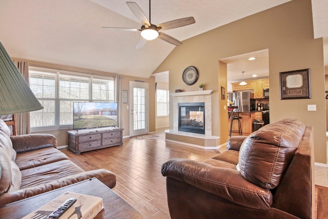 living room featuring a fireplace, a wealth of natural light, light hardwood / wood-style floors, and ceiling fan