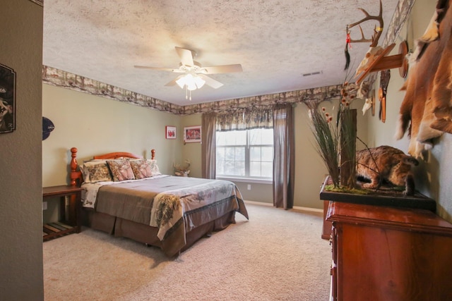 bedroom with ceiling fan, light colored carpet, and a textured ceiling