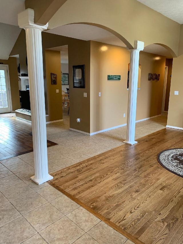 interior space featuring decorative columns, vaulted ceiling, and light hardwood / wood-style flooring