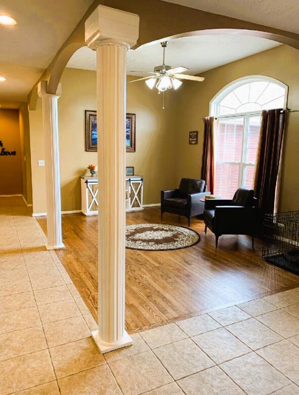 interior space featuring decorative columns, light tile patterned floors, ceiling fan, and beam ceiling