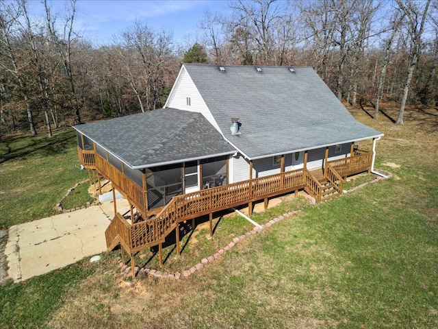 rear view of property featuring a garage, a lawn, and a sunroom