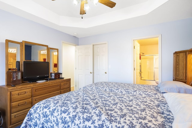 bedroom with connected bathroom, a raised ceiling, and ceiling fan