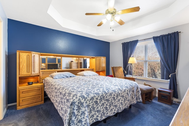 carpeted bedroom with ceiling fan and a tray ceiling