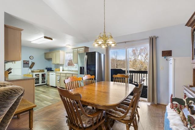 dining area featuring a chandelier, light wood-type flooring, vaulted ceiling, and beverage cooler