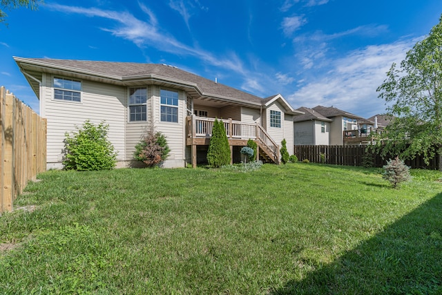 rear view of house featuring a lawn and a deck