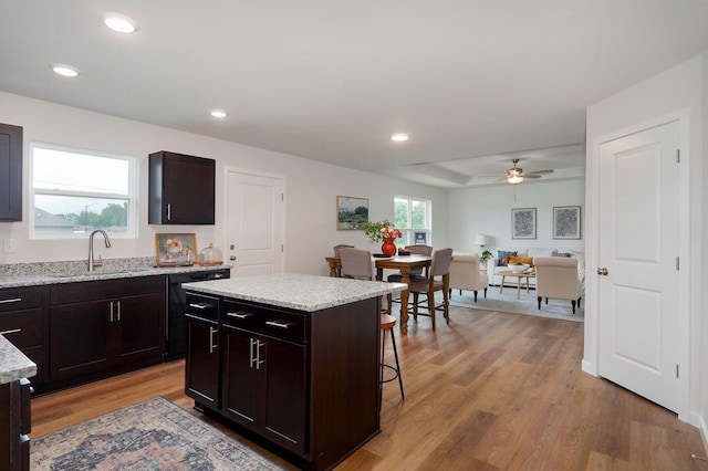 kitchen with light wood-type flooring, dark brown cabinetry, ceiling fan, sink, and a center island