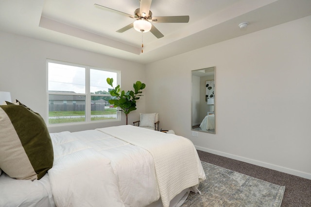 carpeted bedroom featuring ceiling fan and a tray ceiling