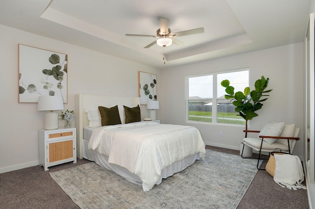 carpeted bedroom featuring a raised ceiling and ceiling fan