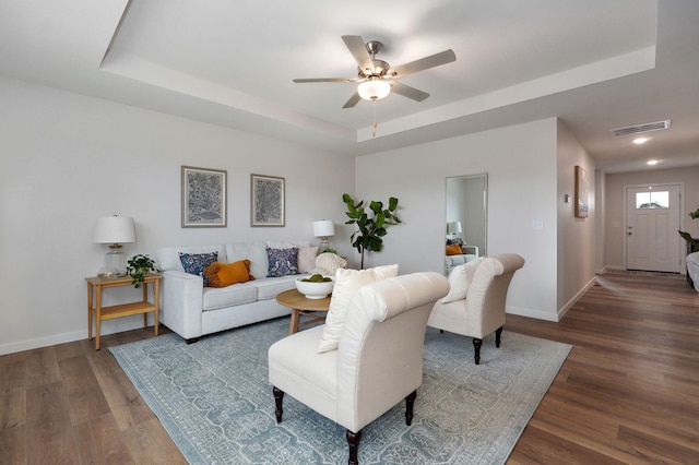 living room featuring a tray ceiling, ceiling fan, and dark hardwood / wood-style floors