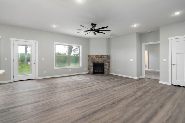 unfurnished living room featuring ceiling fan, light hardwood / wood-style floors, and a stone fireplace