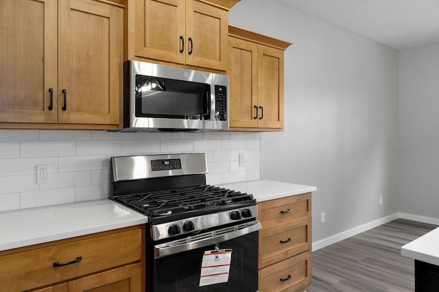 kitchen with decorative backsplash, hardwood / wood-style flooring, and appliances with stainless steel finishes