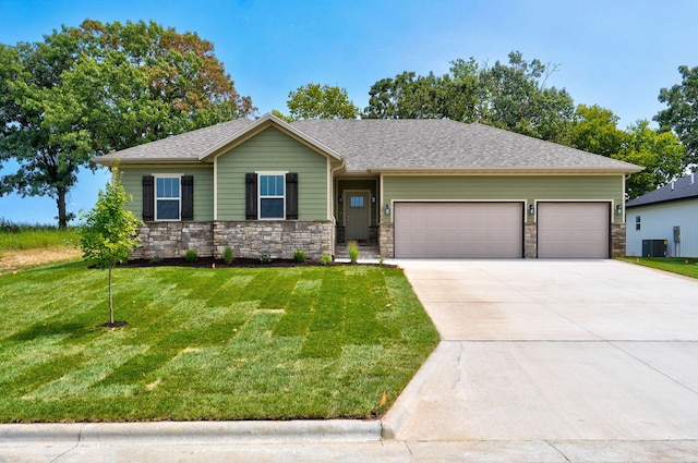 view of front of property with a front yard, central AC unit, and a garage