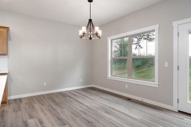 unfurnished dining area featuring light hardwood / wood-style floors and an inviting chandelier