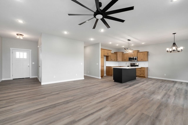 kitchen featuring ceiling fan with notable chandelier, pendant lighting, a center island, and wood-type flooring