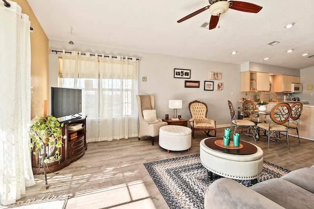 living room with ceiling fan, sink, and light hardwood / wood-style floors