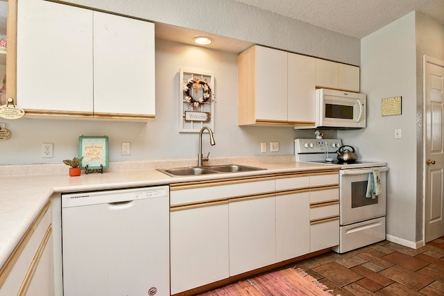 kitchen featuring white cabinets, a textured ceiling, white appliances, and sink